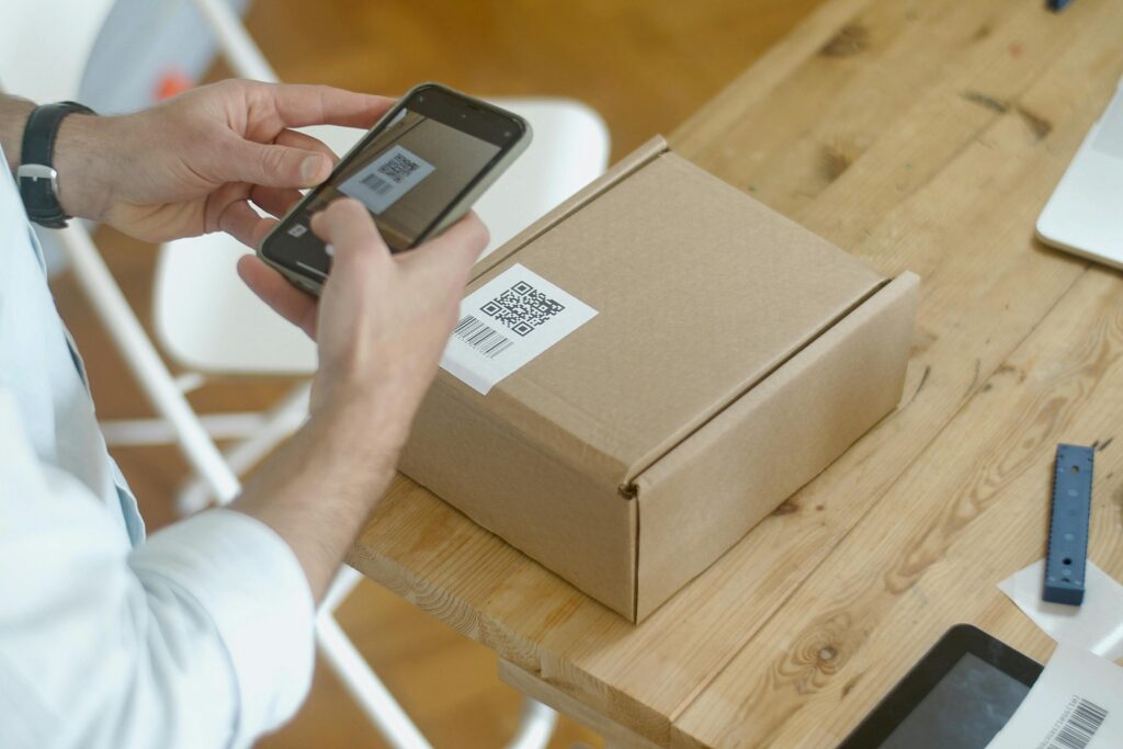 pexels-photo-7289717-7289717 A person uses a smartphone to scan a QR code on a package in an online store setting.